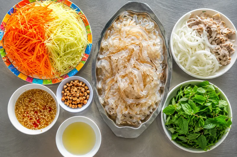 Cách làm nộm sứa ngon bắt đầu từ sứa đã sơ chế, xoài xanh, cà rốt, dưa chuột, rau thơm và lạc rang.
